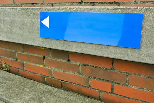 Blue sign with arrow on brick wall. Empty as a texture.