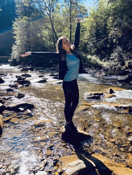 young woman walking in the woods among mountains and stream