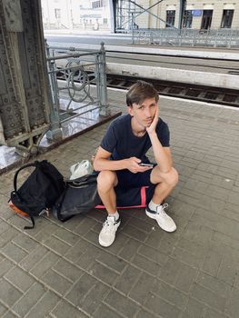 young man sitting on the bag on the railway station