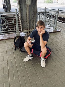 young man sitting on the bag on the railway station