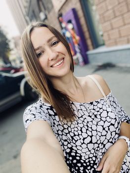 Young smiling woman doing selfie on the city street