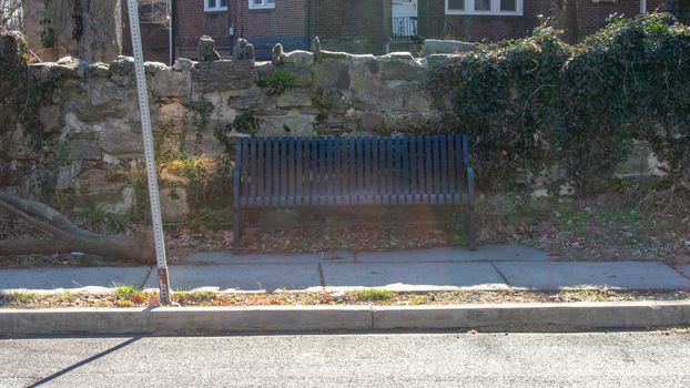 A Park Bench in Front of a Cobblestone Wall in a Suburban Neighborhood