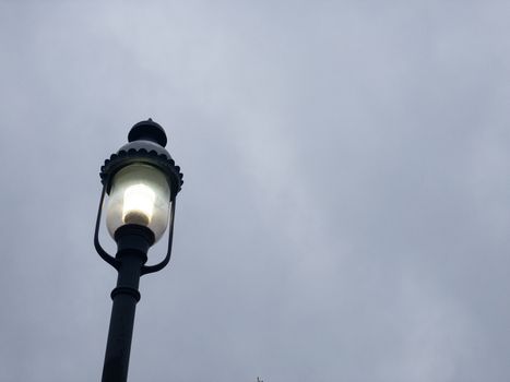 An Old Fashioned Black Metal Street Lamp on a Gray Overcast Sky