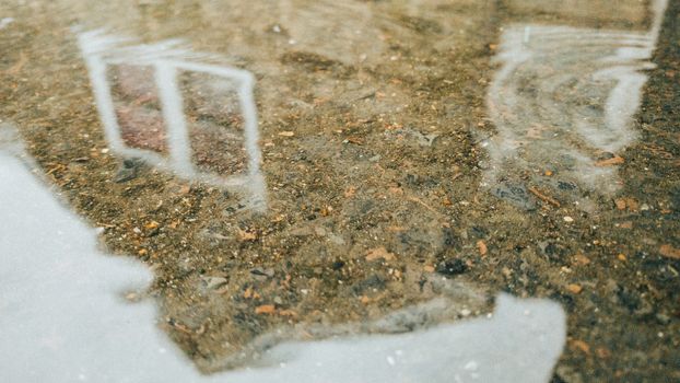 A Cobblestone Building Reflecting in a Puddle on a Rainy Day