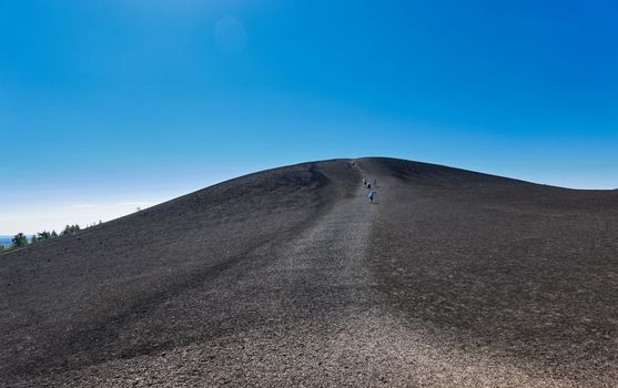 People hiking to the top of Inferno Cone at Craters of the Moon National Park.