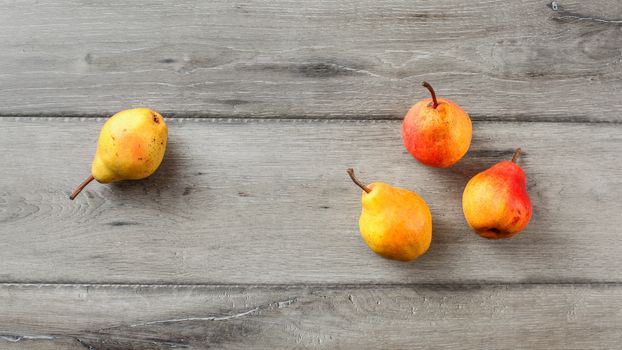 Table top view on four ripe pears placed on gray wood desk.