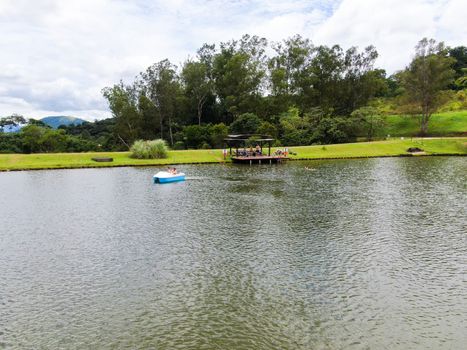 Aerial view of little wood cabana next the lake in the valley, with family enjoying relax moment, swimming and fishing. Monte Alegre Do Sul, Brazil. 