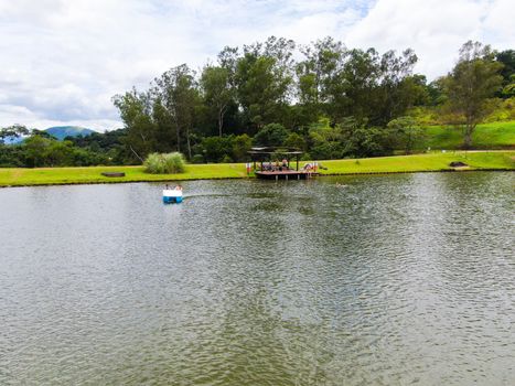 Aerial view of little wood cabana next the lake in the valley, with family enjoying relax moment, swimming and fishing. Monte Alegre Do Sul, Brazil. 