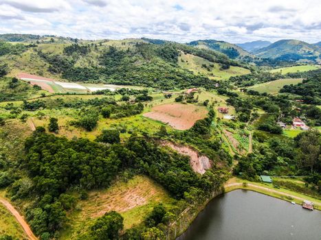 Aerial view of valley with lake, forest and villas in tropical country. Green mountain with forest on Brazil