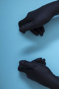 Hand holding or showing something in black nitrile protective gloves 