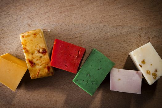 Pieces of colorful cheeses on a wooden background