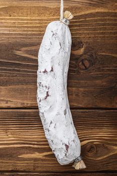 Salchichon sausage on light wooden background, flat lay.