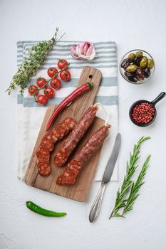 Traditional chorizo cuts with spices and ingredients on white surface, flat lay.