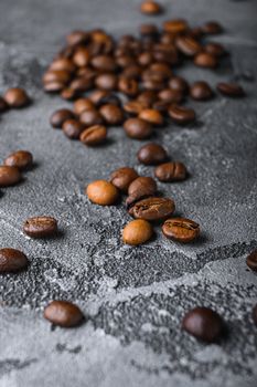 Roasted coffee beans on grey textured background.