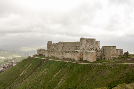 Crac de chevalier Syria exterior against grey clouds 2009 photographed before the war was built by the Hospitaller Order of Saint John of Jerusalem from 1142 to 1271 the best-preserved example of the Crusader castle. High quality photo