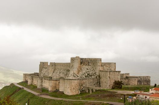 Crac de Chevalier exterior Syria against grey clouds 2009 photographed before the war was built by the Hospitaller Order of Saint John of Jerusalem from 1142 to 1271 the best-preserved example of the Crusader castle. High quality photo