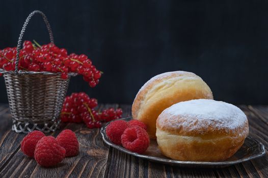Berliner jelly filled doughnut with raspberry and redcurrant on wooden background.