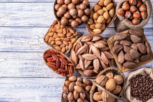 Various nuts, vegetarian food in wooden bowls, top view on old wooden background.