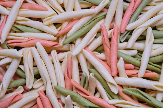 Uncooked rotini or fusilli pasta. Italian egg pasta as background.