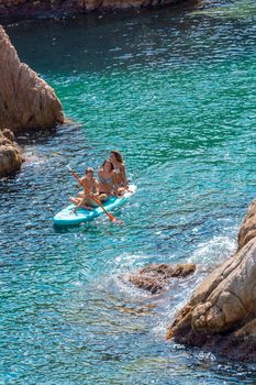 Sant Feliu de Guixols, Spain : 02 Sept 2020: Three young girls go paddle surfing in the  Village of Sant Feliu de Guixols at Costa Brava in Catalonia,Mediterranean Sea,Spain in summer 2020