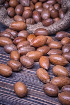 Pecannuts in bag, vegetarian food in wooden bowls, on old wooden background.