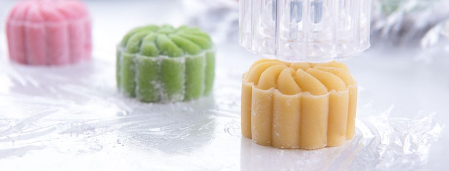 Young woman is making colorful snow skin moon cake, recipe of sweet snowy mooncake, traditional savory dessert for Mid-Autumn Festival, close up, lifestyle.