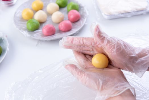 Young woman is making colorful snow skin moon cake, recipe of sweet snowy mooncake, traditional savory dessert for Mid-Autumn Festival, close up, lifestyle.