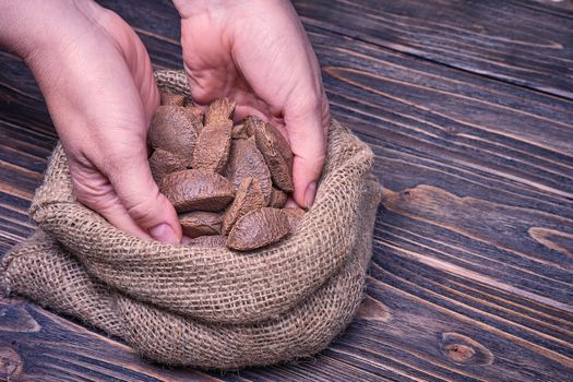 Close up woman hand holds paranuts nut on a wooden background.