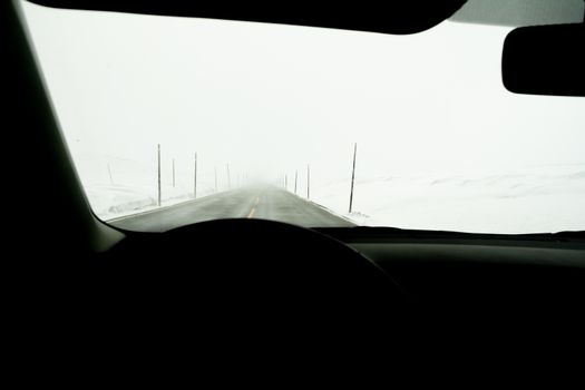 Car interior point of view on road cleared from snow and ice, but piled up on the side of the road. Winter driving.