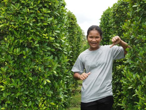 Portrait of a girl standing with a smile In the green bushes.