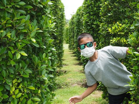 Portrait of a boy wearing black glasses And put on a protective mask On a green background.