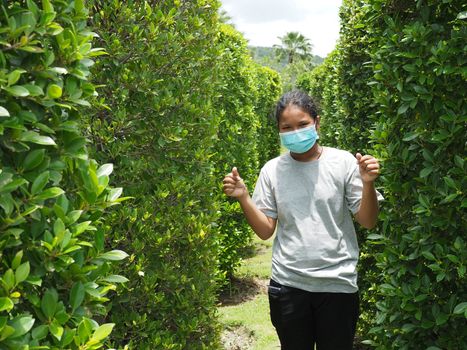 A portrait of a girl wearing a protective mask. On the background is a green bush.