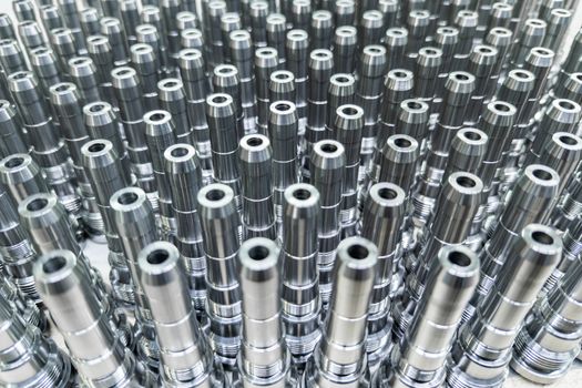 Shiny long steel parts full frame background, clean steel threaded rods after fine cnc turning standing vertically.