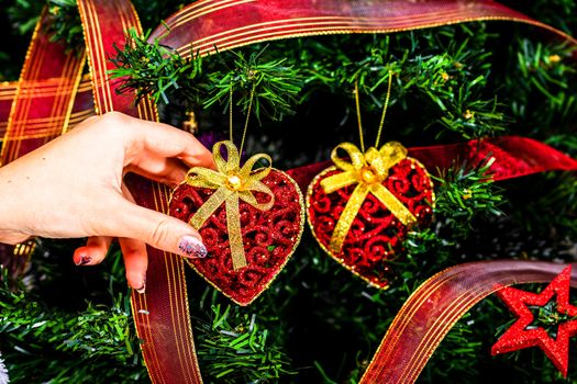 Decorating Christmas tree, hand putting Christmas decorations on fir branches. Christmas hanging decorations.