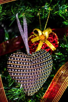 Hand putting heart shaped Christmas decorations on fir branches decorating Christmas tree, Christmas hanging decorations.