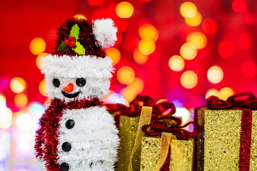 Snowman Christmas figurine near glittery gifts isolated on blurred background of lights. Christmas decorations isolated