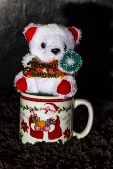 Decorated teddy bear in a Christmas cup isolated on black.  Bucharest, Romania, 2020.