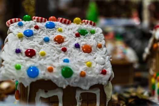 Colorful gingerbread house isolated on blurred background with Christmas decoration.