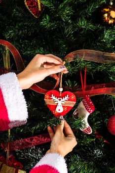 Decorating Christmas tree, hand putting Christmas decorations on fir branches. Christmas hanging decorations.