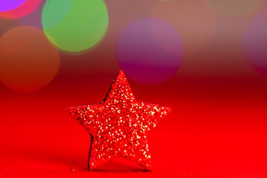 Red glittery decoration in a colorful Christmas composition isolated on background of blurred lights.