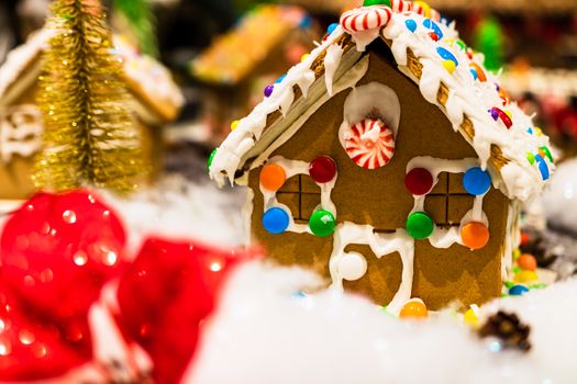 Colorful gingerbread house isolated on blurred background with Christmas decoration.