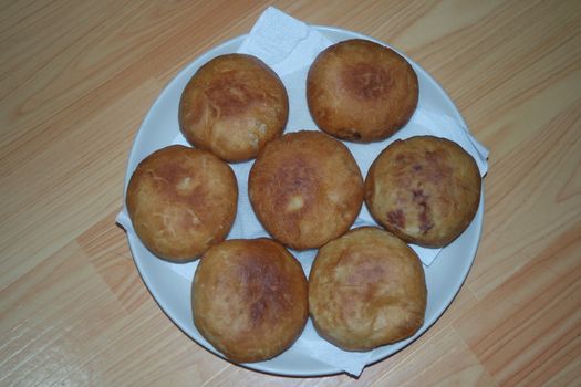 Closeup view of homemade tasty potato bread rolls bun placed in a white plate over a wooden floor.