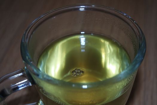 Glass cup having brewed fragrant green tea or qehwa or qahwa on the wooden floor. It is served with sugar or honey and nuts