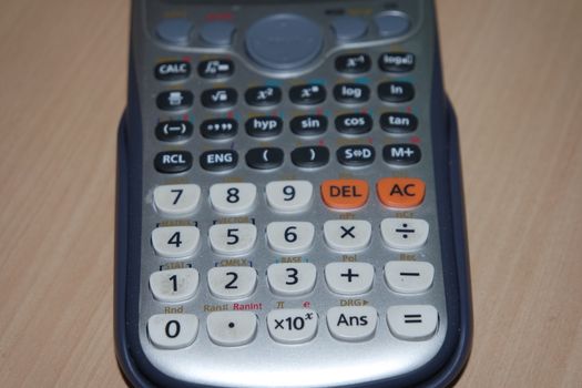 Calculator with colored keys or buttons isolated on a wooden background