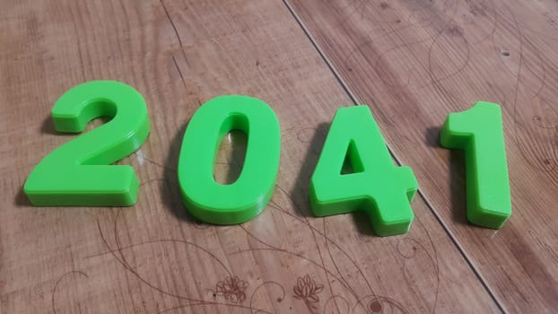 Plastic colored alphabets making words 2041 are placed on a wooden floor. These plastic letters can be used for teaching kids.