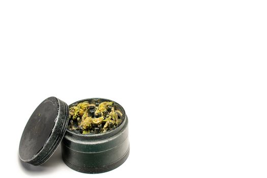 A Black Grinder Full of Cannabis With the Lid Leaning on its side