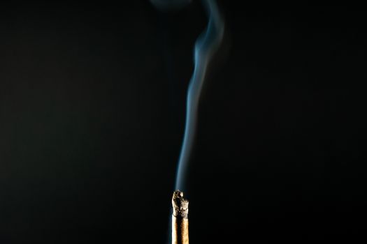 A Cannabis Cigar With Smoke Flowing From it on a Black Background