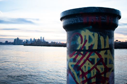 A Graffiti Tagged Pole at Graffiti Pier With the Philadelphia Skyline and a Dramatic Sunset Behind It