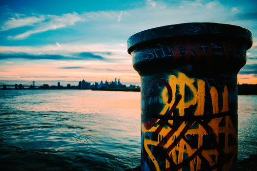 A Graffiti Tagged Pole at Graffiti Pier With the Philadelphia Skyline and a Dramatic Sunset Behind It