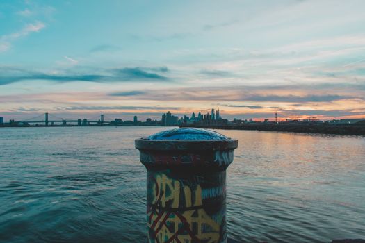 A Graffiti Tagged Pole at Graffiti Pier With the Philadelphia Skyline and a Dramatic Sunset Behind It